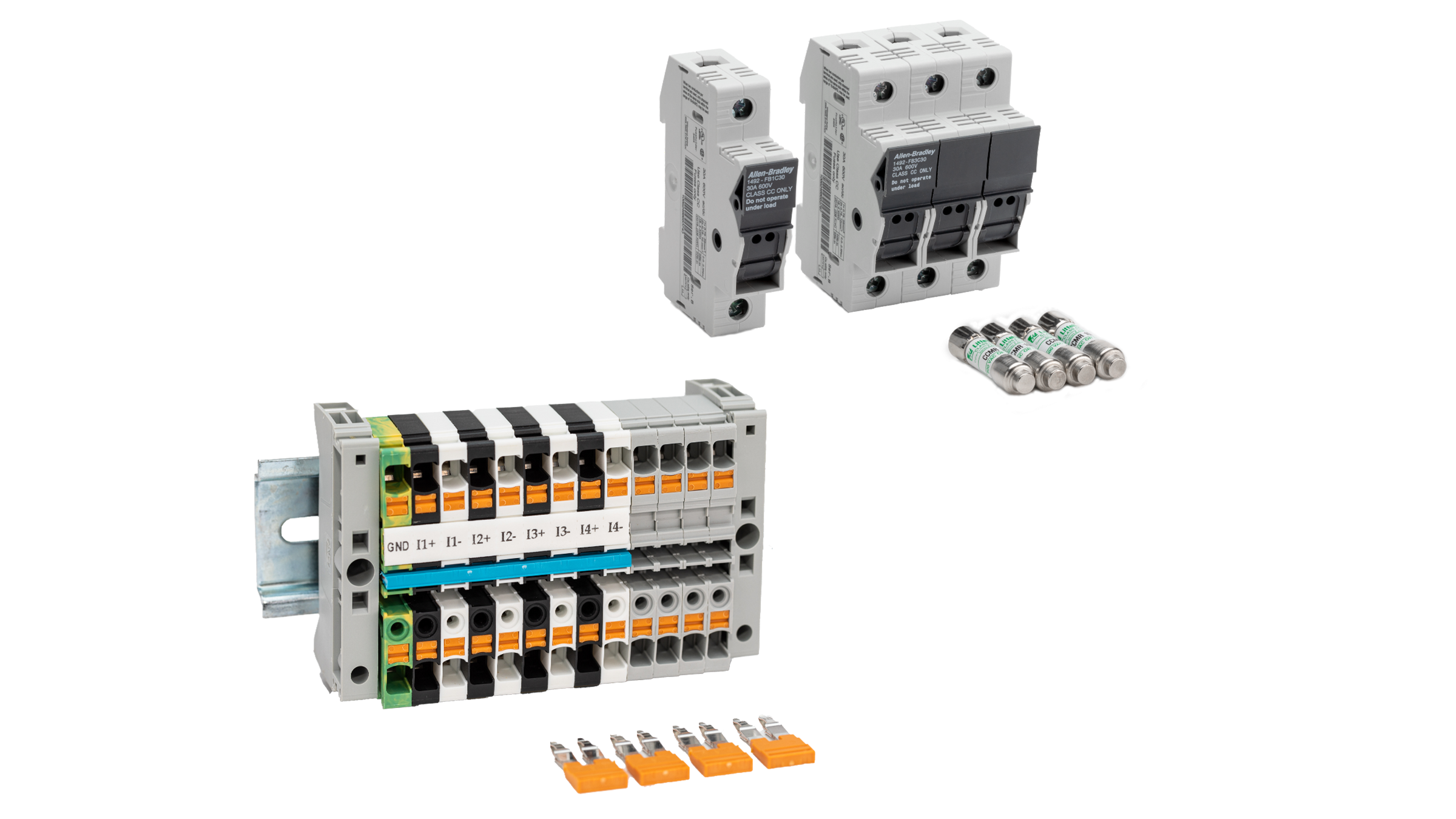 Photo de groupe du kit d'accessoires PowerMonitor avec un seul bloc de court-circuitage et quatre cavaliers orange retirés de la base du bloc au premier plan, un seul fusible de 1 A et trois blocs de 10 A avec leurs fusibles correspondants à l'arrière-plan