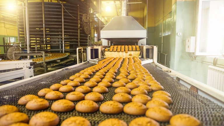 Pasteles en una correa transportadora o línea automática, proceso de hornear en una planta de fabricación de alimentos