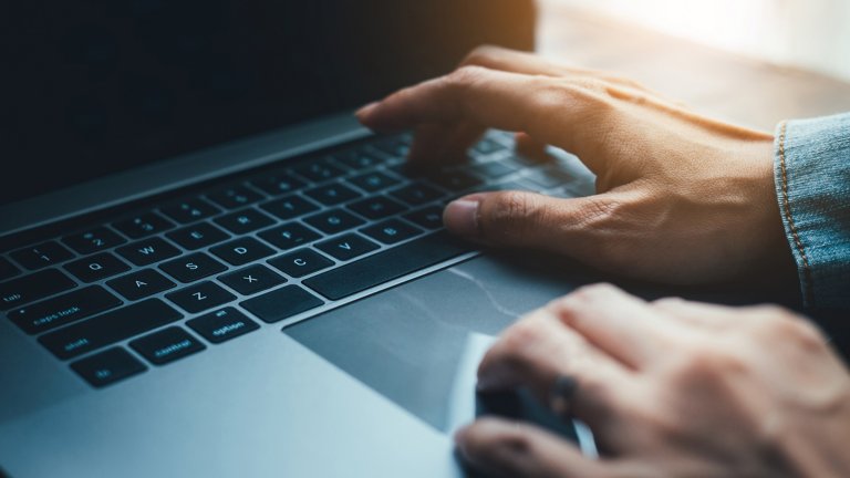 Gros plan des mains d’un homme utilisant le clavier d’un ordinateur portable.