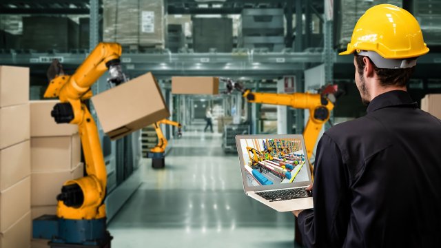 Trabajador en un almacén revisando una simulación Emulate3D en la pantalla de una computadora portátil.