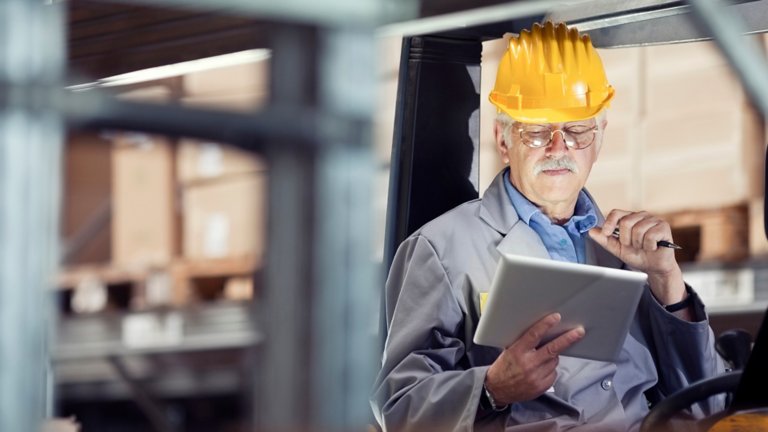 forklift operator at warehouse reviewing  the inventory with the help of digital tablet