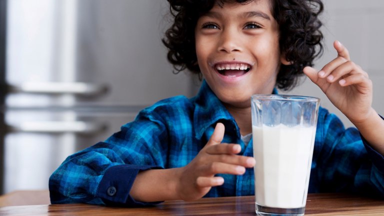 smiling child sitting at a table with a glass of milk