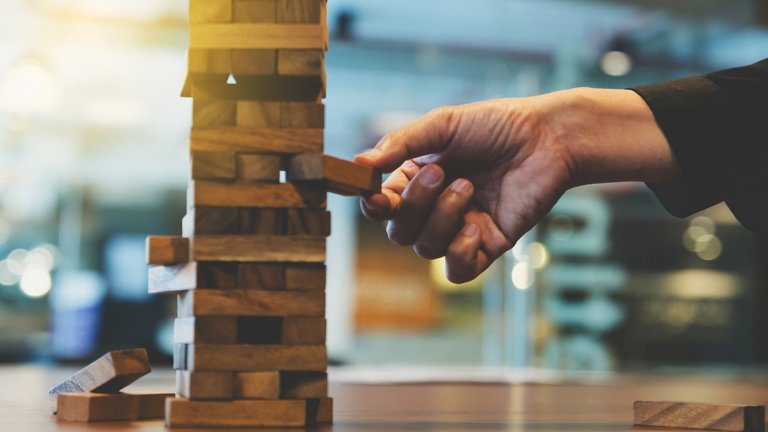 Persons hand pulling out Jenga Piece