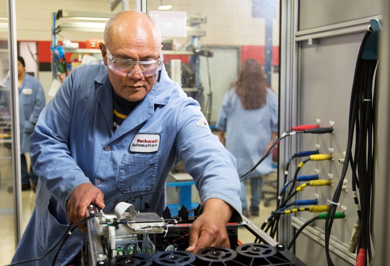 Tecnico uomo in camice blu che esegue test automatizzati sull’unità industriale durante il processo di riparazione