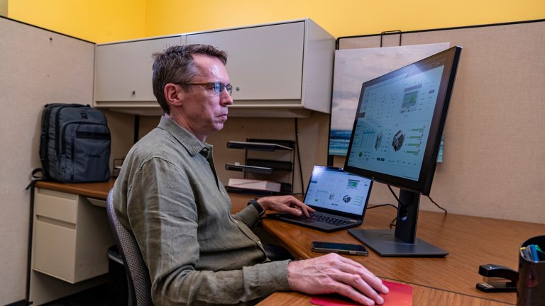 A man is using FactoryTalk Optix software on a PC while sitting behind a desk.