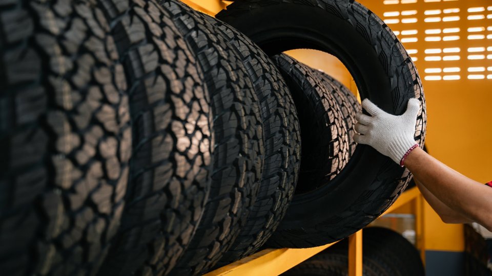 hand of a tire changer lifting a car tires out of a warehouse.