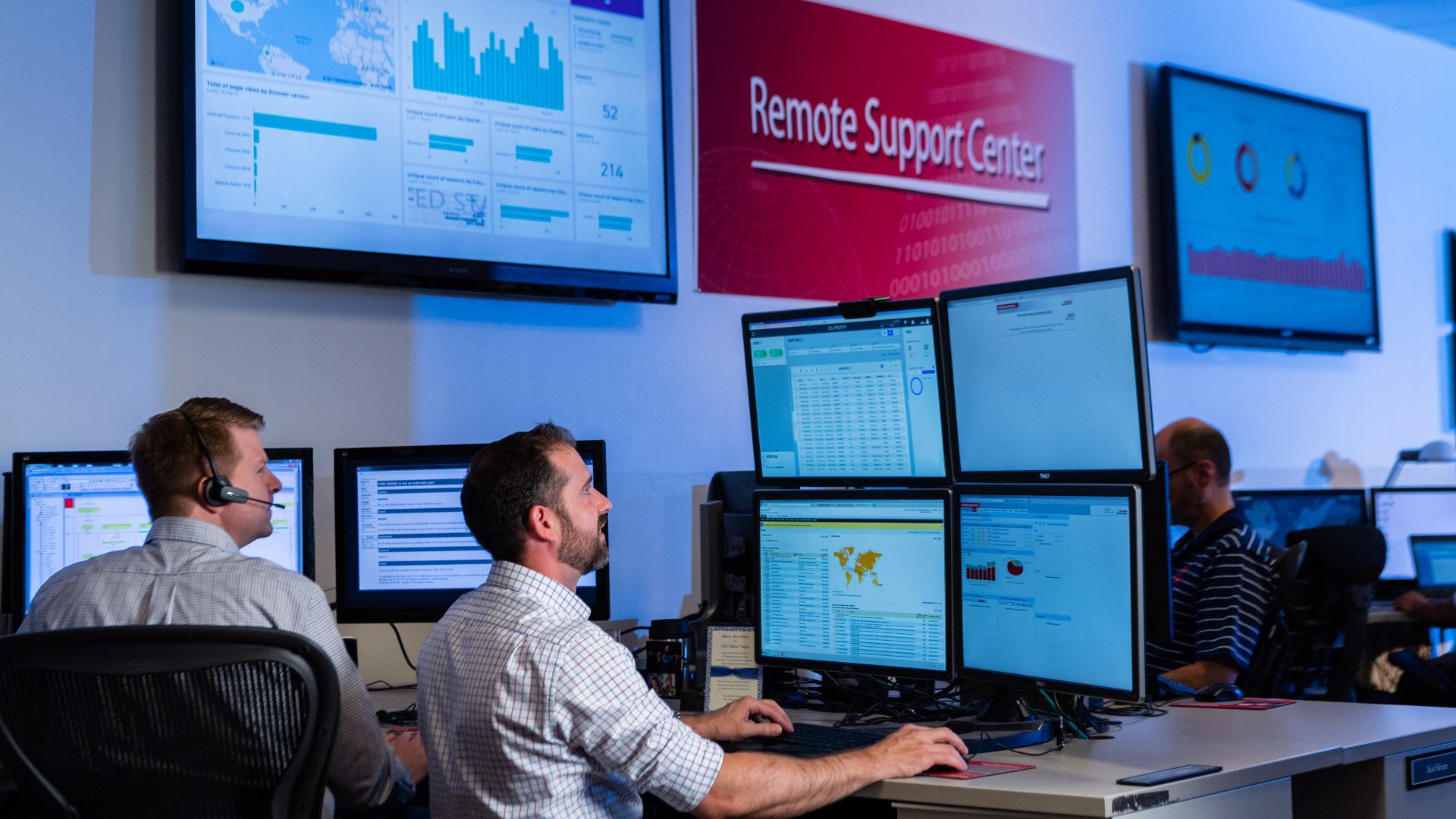 Employees in the RA Remote Support Center, wearing headphones and looking at monitors