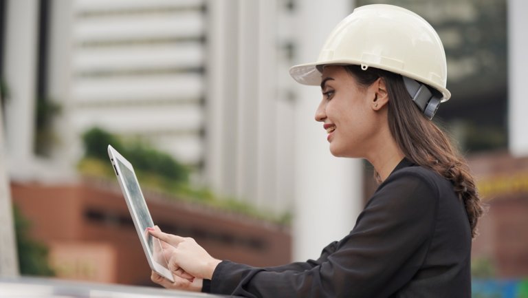 woman engineer wearing white helmet at construction site use computer tablet
